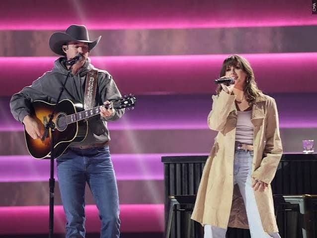 Ella Langley singing a duet with a guitarist in a cowboy hat, both at microphones under pink stage lights